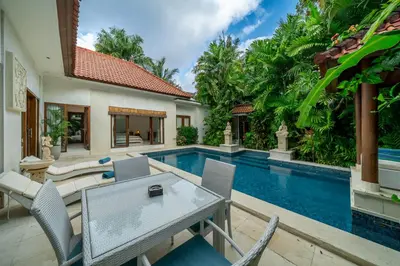 an outdoor patio with a table and chairs next to a swimming pool at Villa Nemia Seminyak in Seminyak