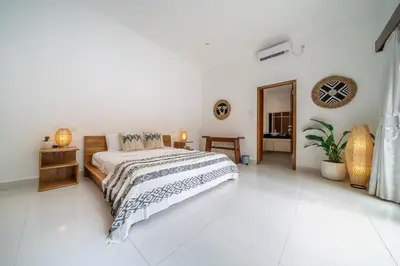 a white bedroom with a bed and a mirror at Villa Nemia Seminyak in Seminyak
