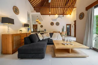 a living room with a black couch and a wooden table at Villa Nemia Seminyak in Seminyak