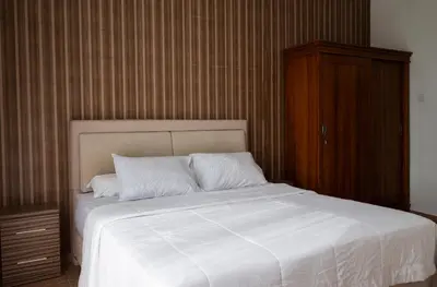 a bedroom with a white bed with a wooden cabinet at Villa with view rooftop in Nusa Dua Bukit in Nusa Dua
