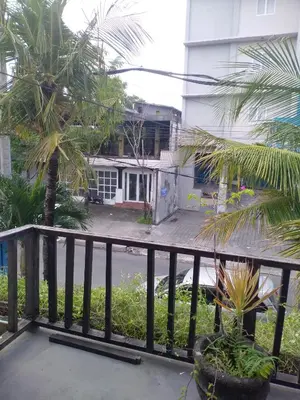 a balcony with palm trees and a building at Seminyak Apartment by LBV in Seminyak