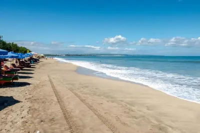 a beach with chairs and umbrellas and the ocean at OYO 1755 De'balcon Accomodation Near Ngurah Rai Airport in Ngurah Rai International Airport