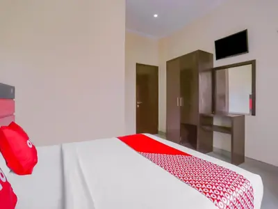 a bedroom with a large white bed with a red blanket at Hotel O Ari Beach Inn in Legian