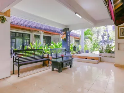a patio with benches and tables in a house at Hotel O Ari Beach Inn in Legian