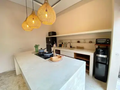 a kitchen with a white counter top and two lights at Luminara villa in Canggu