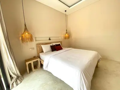 a bedroom with two beds and two pendant lights at Luminara villa in Canggu