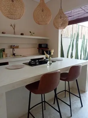 a kitchen with a counter with two chairs and a table at Luminara villa in Canggu