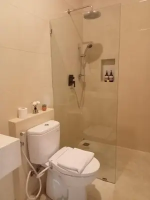 a white bathroom with a shower and a toilet at Luminara villa in Canggu