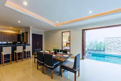 a dining room with a table and a swimming pool at Divija 2 BR Private Pool Villa in Seminyak
