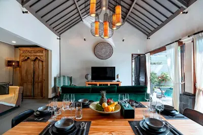 a dining room with a table and a green couch at Villa Damira in Seminyak