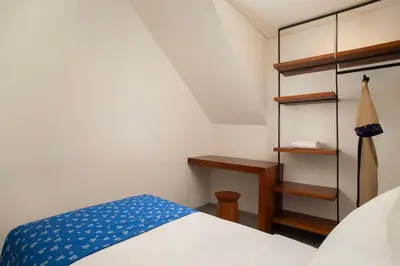 a small bedroom with a bed and a desk at Dialoog Seminyak in Seminyak