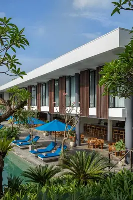 a hotel with chairs and umbrellas next to a pool at Dialoog Seminyak in Seminyak