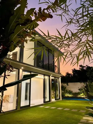 a house with large windows and a lawn at Villa Noeul Seminyak - Fast Wifi And Private Pool in Seminyak