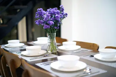 a table with plates and a vase of purple flowers at Villa Noeul Seminyak - Fast Wifi And Private Pool in Seminyak