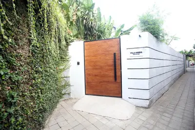 a wooden door in a fence with a hedge at Villa Noeul Seminyak - Fast Wifi And Private Pool in Seminyak