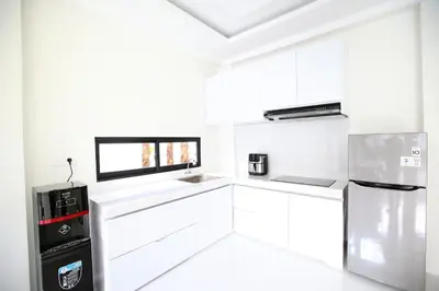 a white kitchen with white cabinets and a refrigerator at Villa Noeul Seminyak - Fast Wifi And Private Pool in Seminyak