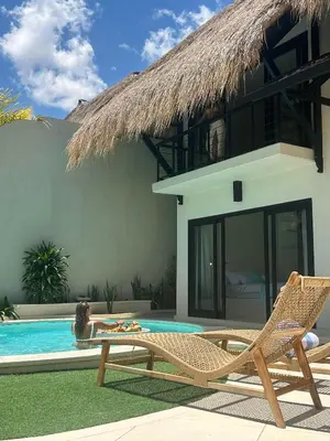 a woman laying in a swimming pool next to a house at Villa Malicott Athena - 3C in Seminyak