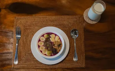 a bowl of cereal and fruit on a napkin with a cup of milk at Akhira One Seminyak in Seminyak