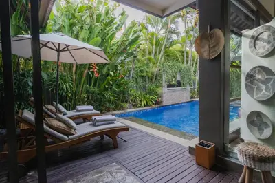 an outdoor patio with a pool and chairs and an umbrella at Akhira One Seminyak in Seminyak
