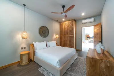 a bedroom with a bed and a ceiling fan at Villa Amanora & Amaluna - 2 Stunning Villas, 9 Bedrooms for Groups in Canggu