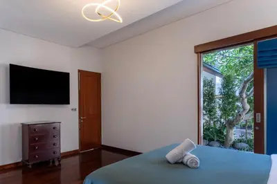 a bedroom with a bed and a tv and a window at Rumah Impian Villa by Betterplace in Canggu