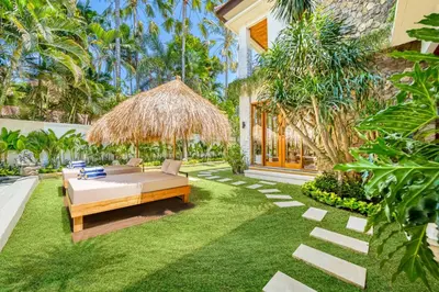 a backyard with a bed and a straw umbrella at Villa Chicago Brand new 7 BDR private pool in Seminyak