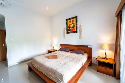 a bedroom with a bed and two night stands and two lamps at Ayu Guest House 2 in Canggu
