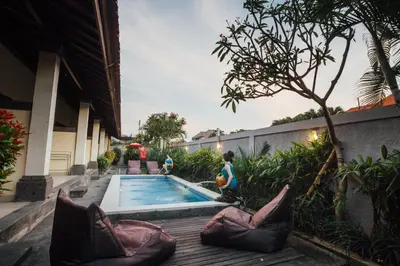 a woman is standing next to a swimming pool at Ayu Guest House 2 in Canggu