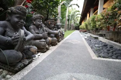 a row of statues sitting on the side of a road at Ayu Guest House 2 in Canggu