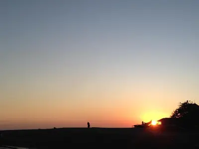 a person standing in a field at sunset at Ayu Guest House 2 in Canggu