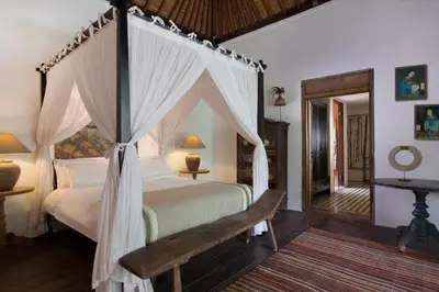 a bedroom with a canopy bed with a bench and a mirror at Villa Mamoune in Umalas