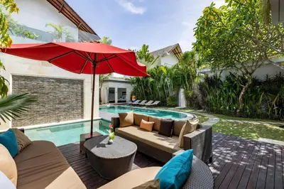 a patio with a couch and an umbrella next to a swimming pool at Spacious 4BR Villa with Pool in Central Seminyak in Seminyak