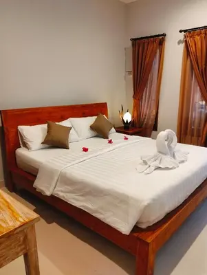 a bedroom with a large bed with white sheets and roses at De Jaya in Kerobokan