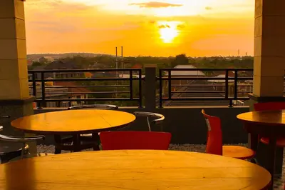 a patio with tables and chairs with a sunset in the background at Ramantika Bali House in Jimbaran