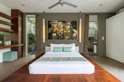 a bedroom with a large white bed with a painting on the wall at Stunning 4 Bed, Butler Service, Security, Central in Seminyak