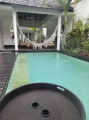 a swimming pool with a chair in front of a house at Rove One-bedroom Pool Villa Seminyak in Seminyak