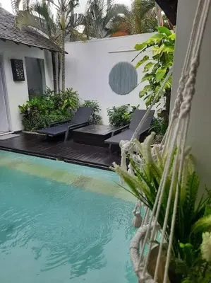 a swimming pool with chairs next to a house at Rove One-bedroom Pool Villa Seminyak in Seminyak