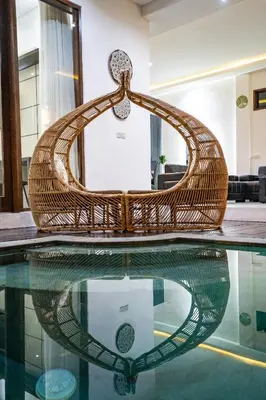 a wicker chair sitting on top of a swimming pool at Villa Liamax by JB villas in Seminyak