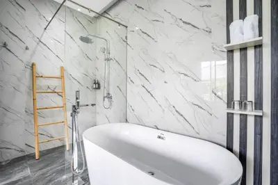 a white bath tub in a bathroom with marble walls at Villa Liamax by JB villas in Seminyak