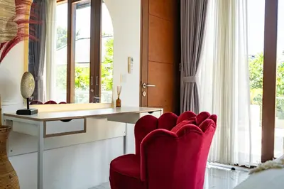 a room with a red chair and a desk at Villa Ashëla by JB Villas in Seminyak