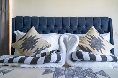 a bed with a blue headboard and two towels at Villa Ashëla by JB Villas in Seminyak