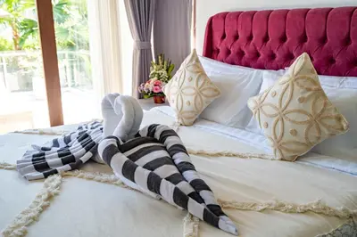 a bed with a red headboard and a black and white blanket at Villa Ashëla by JB Villas in Seminyak