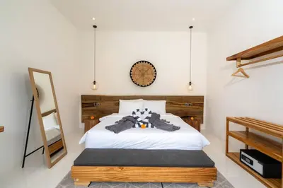a bedroom with a white bed with a wooden headboard at Vajrayana - 10 Min From The Beach, Serene Villa with Pool View in Kerobokan