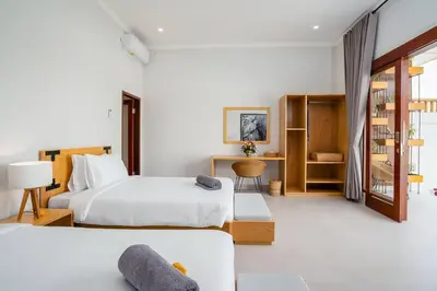 a hotel room with two beds and a desk at Umanala - 5 Min To Beach, Sleek Villa with Spacious Pool Area in Kerobokan