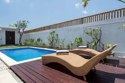 a deck with a pool and chairs next to a house at Umanala - 5 Min To Beach, Sleek Villa with Spacious Pool Area in Kerobokan
