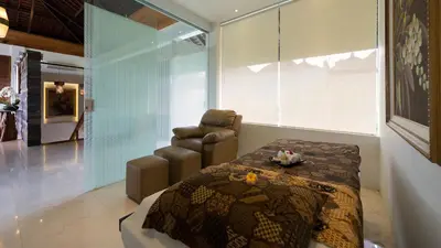 a room with a bed and a chair in it at Villa Aiko in Jimbaran