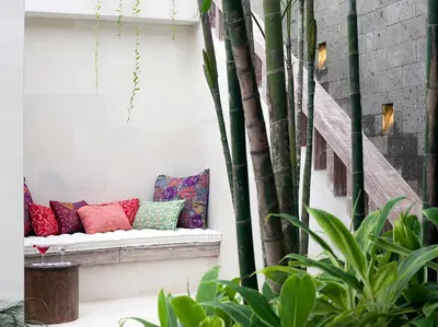a bench with colorful pillows on a patio with bamboo at Villa Adasa by Elite Havens in Seminyak