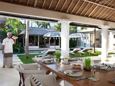 a man standing on a patio with a table with food at Villa Adasa by Elite Havens in Seminyak