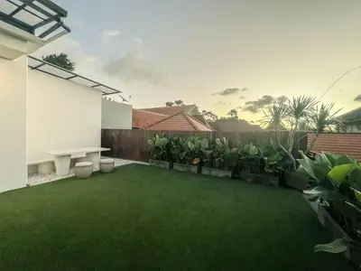 a backyard with green grass and a fence at Cara Villa Bali in Seminyak