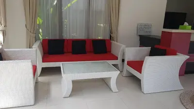 a living room with white chairs and a red couch at Kubu Nesa in Jimbaran